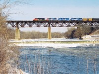 CN 391 crosses the Grand River bridge in Paris, Ontario on the Dundas Subdivision with a colourful consist. The unit’s included 6027, GT 5809, Conrail’s 6660 and 6751. Conrail SD45-2 6660 was on lease to power-short CN while SD50 6751 was working-off horsepower hours owed to CN at the time. 