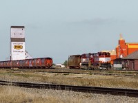Great Western's M420's still in Bay Colony paint scheme make up a train of grain loads for delivery to CP at Assiniboia. The Atco trailer near the unit is company HQ and the wooden building is tool shed, which was freight shed of CP's now demolished 3 story station