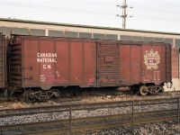Forty foot steel boxcars were once a very common type of railcar, moving an extremely wide range of goods.<br>
But it's quite a while since I last saw a WW2 era boxcar in Maple Leaf CNR Serves All Canada scheme.<br><br>
Several of these veterans were in Oakville in 1993, retaining roofwalks, high brake wheels, "friction" plain wheel bearings, and wearing CN-service car numbers - suffixed "R" for restricted (not for interchange).<br>
This example CN 72701R was built in June 1944, and continued in revenue service into the KarTrak colour barcode era (1967-1977). The former car number is over-painted, though some of the digits can be made out. I determined it used to be CN 467227 by magnifying and interpreting the barcode.<br>
One of the coil springs below the faded car number has been replaced by something different.<br>
There appears to be a triangular hole just to the lower right of the car loading door.<br>
The car to the left was formerly CN 473453, built in May 1937.<br><br>
For months (perhaps years) this pair was parked to the west of Oakville VIA Station, alongside this building marked CN Signals and Communications.<br>
As of 2020 these cars are long gone, the north-side siding tracks are gone, and the building has gone.<br> 
In their place is a third mainline track, and the north Oakville platform extends past here for 12-coach GO trains.
