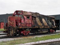 "Well, here's another fine mess you've gotten me into."<br>
This hump-assigned GP38-2 was seen outside Macmillan Yard Diesel Shop on shop trucks, looking very beat up.<br>
It is hoped that nobody was seriously injured.<br><br>
Hump pullback speeds don't need to be really fast, but a lot of energy got absorbed by CN 7500.<br>
For hump switching the only active brakes are on the engines and slugs; a long cut of cars cannot be stopped as fast as a train. If anyone has information about this particular mishap, please comment.<br><br>
Not far away was hump slug CN 512 with serious body damage but still on its own trucks.<br>
A pair of damaged Blomberg trucks off CN 7500 were loaded on flatcar CN 667502.<br><br>
The next time I saw CN 7500 was mid-April 1995. It was back at Mac Yard in clean CN North America paint scheme (without map), fully repaired and not showing noticeable scars from its crash.<br><br>
I used to enjoy the privilege of taking pictures here, but things have changed; the last time I got permission was in the latter 1990's.
