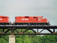 A pair of CP Rail GP9u locomotives lead their train east across Sixteen Mile Creek in Oakville.<br>
Presumably exercising trackage rights on CN's Oakville Sub between Hamilton Jct and Toronto (Canpa).<br>
I read that this arrangement began in 1896 continuing for 99 years - after that things changed.<br>
A relic of CP's maroon and grey era is the swoosh over 8242's front-most radiator intake, for the yellow stripe. 