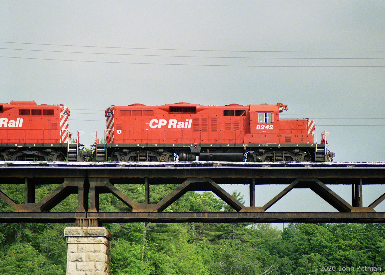 A pair of CP Rail GP9u locomotives lead their train east across Sixteen Mile Creek in Oakville.
Presumably exercising trackage rights on CN's Oakville Sub between Hamilton Jct and Toronto (Canpa).
I read that this arrangement began in 1896 continuing for 99 years - after that things changed.
A relic of CP's maroon and grey era is the swoosh over 8242's front-most radiator intake, for the yellow stripe.