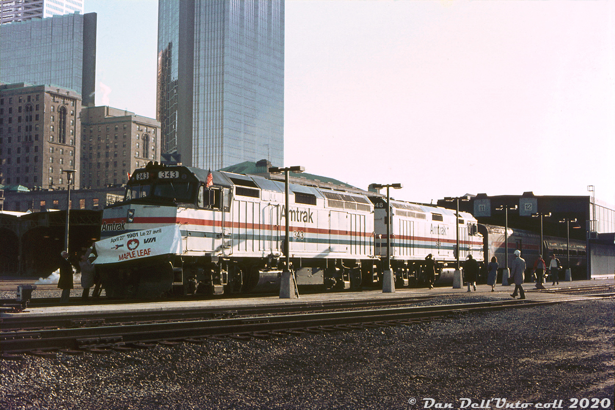 The first run of the new VIA-Amtrak "Maple Leaf" cross-border train service ran on April 26th 1981 with Amtrak F40PH 344, a baggage and six Amfleet cars. But, the next day on April 27th was a ceremonial run with Amtrak F40PH's 343 & 348, a baggage, 9 Amfleets and a private car on the tail end. Here, the train is shown on Track 12 at Toronto's Union Station at sunrise, with a ceremonial Maple Leaf banner being put up on the lead unit (for photo-ops? another photo of the train taken passing through Hamilton that day shows it removed from the lead unit). Also note the dual US-Canadian flags. The short baggage car behind the lead units is one of Amtrak's conversions from a former US Army ambulance kitchen car build in the 1950's. Amtrak apparently picked up a bunch of these hardly used cars in the mid-70's and converted some into small baggage cars.

Replacing the old CP/VIA (nee-TH&B) Toronto-Buffalo Budd run, the joint Maple Leaf continues to run to this day, albeit with Amtrak P42's pulling the Amfleets instead of F40's. 

Photographer unknown, Dan Dell'Unto collection slide.