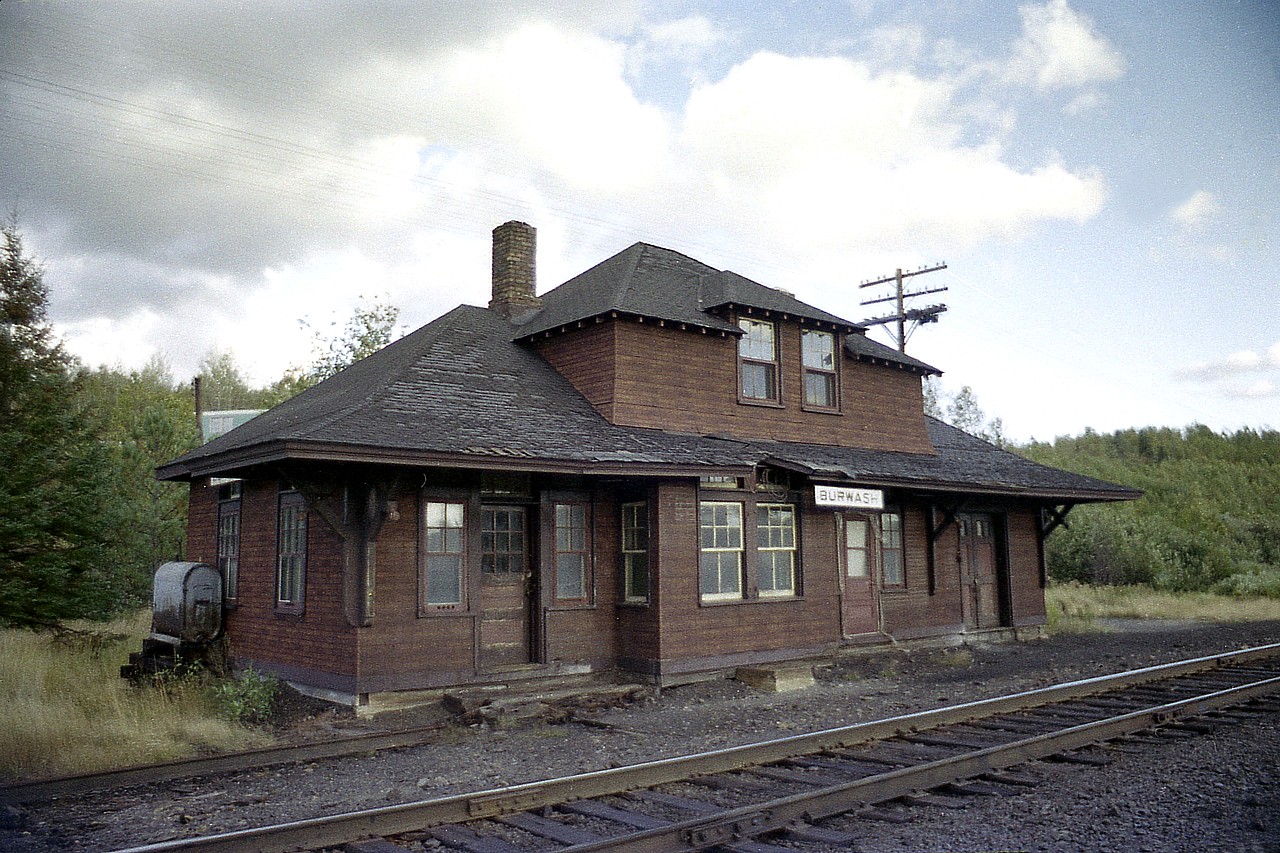 Burwash. Another 'infamous' place, I guess one could say.
  This was the home of the Burwash Industrial Farm; opened in 1914 when 9 German inmates got off the train at Burwash station (Estaire)as the first residents. The station was a mile and a half from the 'farm'.
This "farm" was probably better known as the Burwash Correctional Facility, and its purpose was to give skills and education to inmates by means of having them work an actual "village". They made bread, raised cattle, had vegetable gardens and so on. A sawmill was located there; inmates learned trade, and all the Ontario provincial parks gained their picnic benches from the workers at Burwash.  The "farm" covered thousands of acres, and was remote enough that very few tried to escape. Not only were they a long way from anywhere, escaping thru the bush resulted meeting millions of hungry mosquitoes, overly voracious black flies and other menacing wildlife.:o)
  Despite all the activity and the place being considered self-sufficient, the province decided to close Burwash in 1975; and the little community nearby, Burwash (Estaire area) became a ghost town, as there was no longer a need for a local village to house guards and other support staff.
  When I stopped for this picture in the fall of 1976, it was obvious the old station was for many years unused; and I was somewhat surprised at the lack of broken windows. Maybe someone hoped to save the old place? I don't know what happened to it, but a few years later I was unable to find a trace of it.
