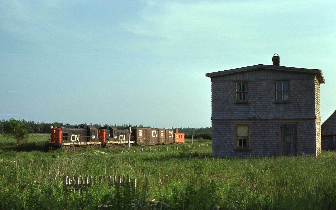 Two CN RSC-13s amble by a typical Up-West house as they near Mileage 77.7, St. Louis, Prince Edward Island on an evening in July 1974.   

At Tignish, Mileage, 84.6, the western end of the Kensington, Sub,  the crew will tie up for the night and start their eastbound 68-mile trip back to Summerside the following morning.  

CN 1734 was built by MLW in 1957 and was the last of 35 RSC-13s.  The units began to be retired in the fall of 1975.  CN used their trucks in a Moncton-based program to create "RSC-18s" as replacements on Maritime branchlines.   CN retired 1734 on Monday, December 15, 1975, and its trucks were mated to RS-18 3864, becoming RSC-18 1765 two days later.  It was retired on Thursday, September 30, 1993.  Cape Breton & Central Nova Scotia bought 1765 in 1995 and it served as a parts source for CBNS RS-18 3716.
