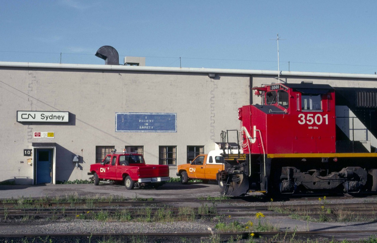 CN M-420 3501 (MLW 5-1973 #M6071-02) poses at the Sydney Shop in the dying days of CN service to Cape Breton in early September 1993.    

In May 1973, the 2501 entered service as the world's first locomotive equipped with a Comfort Cab.  CN worked with both Canadian locomotive builders beginning in the late 1960s to provide increased crash protection for crews as well as electric heating, improved insulation, armchair seats, a refrigerator and hotplate.  After 1973, all newly built road units for CN would include a Comfort Cab.  (See CNR Diesel Locomotives Vol 2, CNRHA 2014, for a detailed history of the Comfort Cab.)  The MR-20a units also featured a freshly designed Zero Weight Transfer (ZWT-2) truck to reduce wheel slip.  Finally, the order for thirty M-420s introduced the diagonal stripes to CN road freight locomotives.    

CN displayed the 2501 for employees at Central Station in Montreal, while 2502 was on display in Sydney in early June 1973.   Beginning in October 1986, CN began a 15-month program in Moncton to lighten the 2500 series units by restricting fuel and sand capacity.  Upon returning to service, CN added 1000 added to their number, reflecting their assignment to secondary duties common to the dwindling number of ageing RS-18s.  The unit was retired on Tuesday, November 25, 1997, and sold in 1998 by CN subsidiary CANAC to the St. Lawrence and Atlantic in Maine.  It operated as their 3501 until the Hudson Bay Railway purchased it on Sunday, April 18, 2004.  The Keewatin Railway running between Flin Flon and Lynn Lake, Manitoba purchased it in 2007 and assigned it the number 2400.  It continues to operate, having borne the number 2402 since 2008.             

In early October 1993, CN began to lease their trackage east of Truro.  Railtex was the initial operator as the Cape Breton & Central Nova Scotia.  Their choice of ex-CN R18s and, particularly, C-630Ms as motive power introduced a golden era between 1993 and 1997 that attracted railfans from around the globe.   In late 2001, Sysco, a provincially owned steel mill closed in Sydney as did nearby coal mines owned by Devco, a federal Crown Corporation.  The closures hugely impacted traffic on the CB&CNS.  By Tuesday, December 30, 2014, Railtex successor Genesee & Wyoming closed operation of the Sydney Sub east of Tupper near Port Hawkesbury on Cape Breton Island's southern shore.