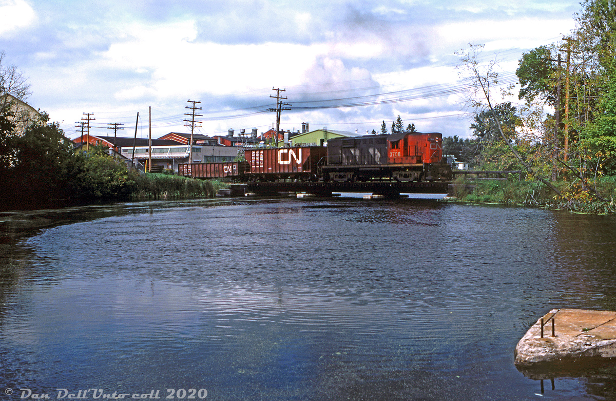 CN RS18 3708 works local freight #590 along the former Thousand Islands Railway line (now known as CN's Gananoque Spur), crossing the Gananoque River between River Street and King Street. The spur line branched off near Cheeseborough at Mile 155.3 of CN Kingston Sub and extended 3.2 miles south into the Town of Gananoque, following the Gananoque River. Interestingly, the line diverged about a mile west of the CN Gananoque station location, once known as "Gananoque Junction".

The Thousand Islands Railway was originally constructed in the 1880's as a way to connect port and lumber facilities in the Village of Gananoque to the Grand Trunk Railway's mainline, and in 1911 GTR took control of the TIR. The name of the line was retained until 1958, and CN continued to operate the line as a spur until dwindling traffic warranted abandonment in 1996, and removal in 1997 (parts of the right of way are now the Gananoque Waterfront Trail).

Keith Hansen photo, Dan Dell'Unto collection (with some colour correction and restoration work done).

For more history on the line, refer to Ray Kennedy's Old Time Trains page here.