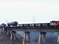 A CN special train with GP9 4596 creeps over the single track Humber River bridge on CN's Halton Sub with a huge load for Ontario Hydro's Darlington Nuclear Power plant which was under construction at the time.  The hoppers were each loaded with about 40 tons of sand for extra braking power.  