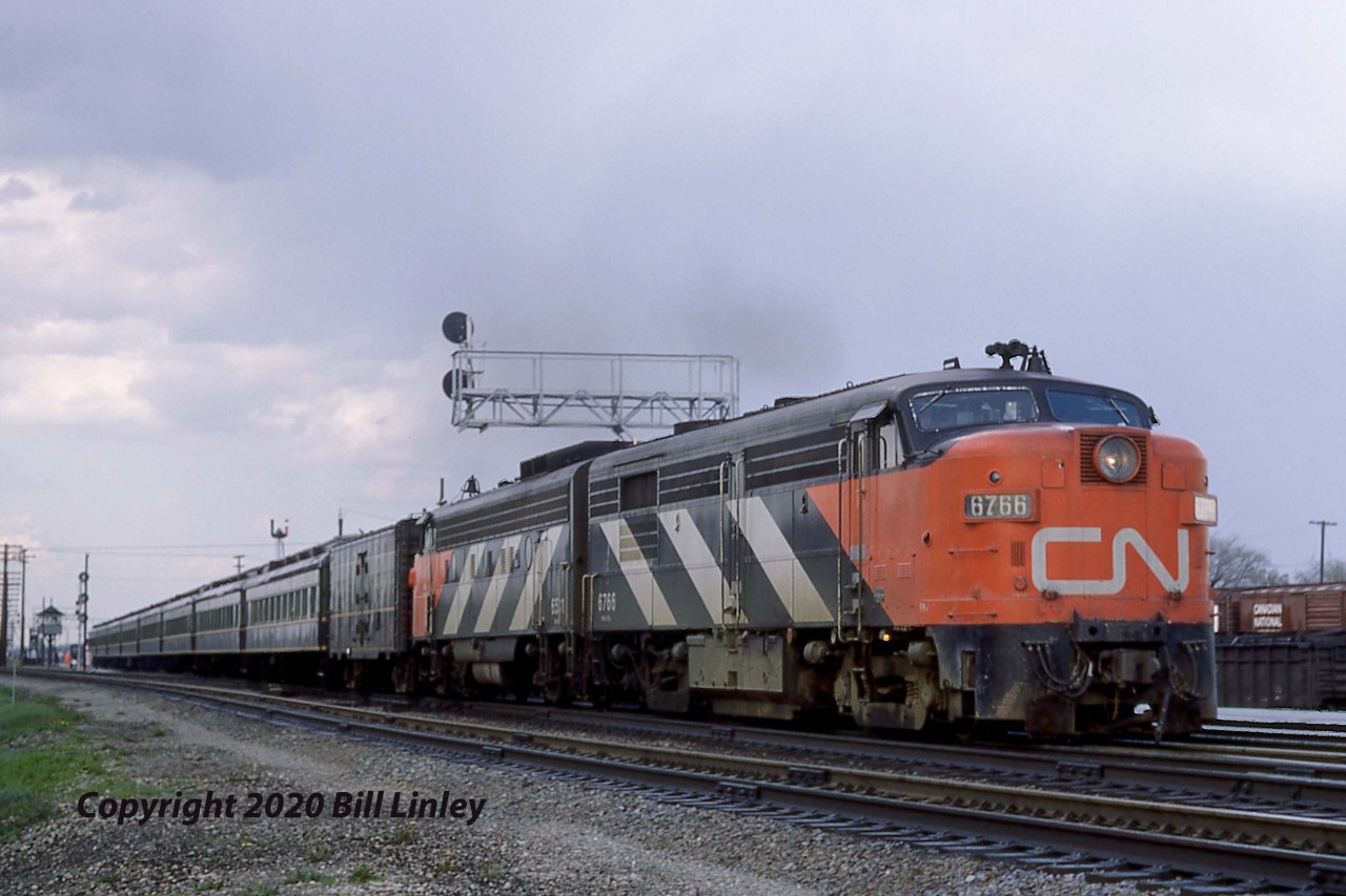 With GO Transit's 1967 debut of service to Oakville, they also replaced CN's two traditional commuter trains on the 39.3-mile route between Toronto and Hamilton, Ontario. 1957-built FPA-4, 6766 pauses with the second last run of Train 989 at Burlington, Mileage 32.2 of the Oakville Sub, at 6.25 p.m. on Friday, May 19, 1967.  

Barely six months later, on Wednesday, November 15, the MPA-18a was wrecked at Drummondville, Quebec and would become the first FPA-4 to be retired.  The 6766 caught fire after it's Train 21, a one-stop Rapido en route from Quebec City to Montreal, met Train 424 head-on.  Trailing FPB-2 6854 survived while RS-18s 3854 and 3882 were also retired on December 31, 1967.  Fortunately, there were no fatalities.

In the foreground, the double-tracked Halton Sub veered off to the north to CN's Toronto [now MacMillan] Yard.