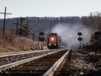 With 2000' of continuous welded rail (CWR) in tow, a pair of venerable SD40-2 workhorses put on a nice show as they charge up the grade at Milton, Ontario. Days that start like this tend to be good ones...