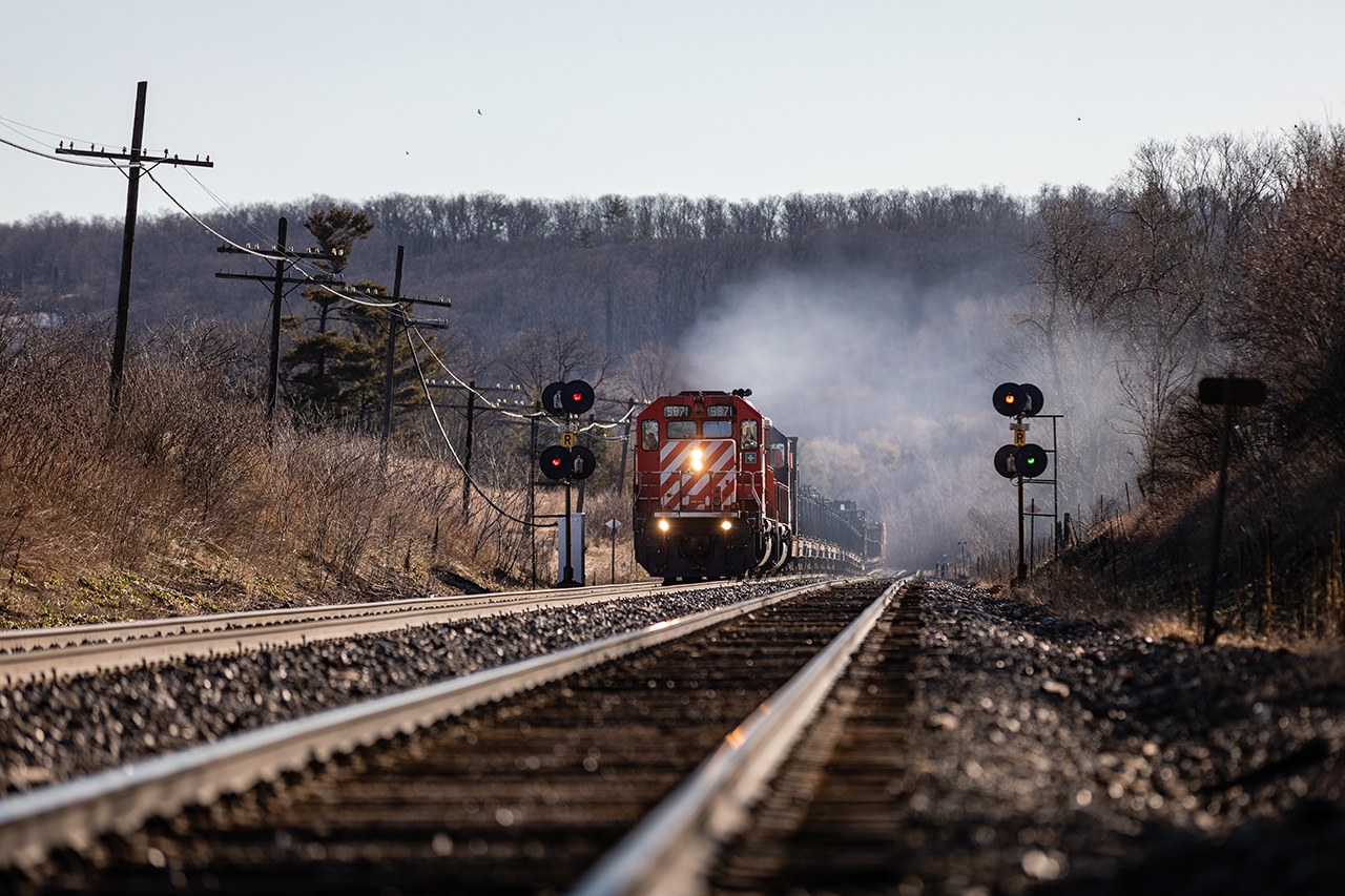 With 2000' of continuous welded rail (CWR) in tow, a pair of venerable SD40-2 workhorses put on a nice show as they charge up the grade at Milton, Ontario. Days that start like this tend to be good ones...