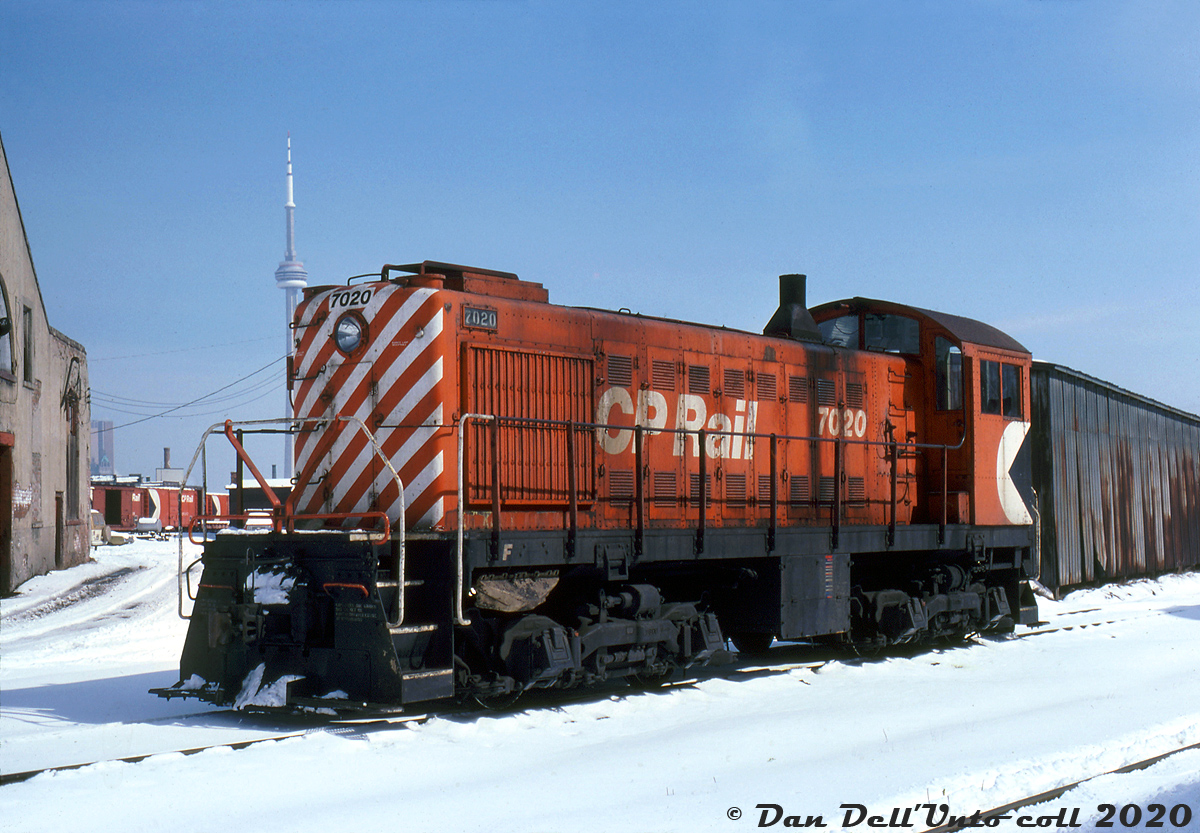 CP Rail Alco S2 7020 idles between duties in the Liberty Village area near CP's Parkdale Yard (note boxcars in the background, with the yard office obscured by the building on the left). The industrial leads in the foreground were for switching the sprawling John Inglis plant off Strachan Avenue, as well as leading to the old TG&B "Wharf Lead" that ran south over the CN Oakville Sub at Cabin E (multiple diamonds) to access the downtown harbourfront trackage. The photographer would have been standing behind the old Hinde & Dauch Paper building off Hanna Avenue.

Located west of downtown Toronto in the parcel of land between Bathurst Street and Strachan Avenue and bordered by the rail lines to the north and south, Liberty Village was an industrial powerhouse for many decades, including contributing to the wartime production efforts. But by the 80's a state of industrial decay had set in, and over time many of the old industries, sidings and spurs, and CP's Parkdale Yard all disappeared. Gentrification came to the area around the early 2000's, with loft conversions and heavy condo construction turning a former gritty industrial area into a trendy and desirable neighbourhood for young professionals working downtown (for a closer look at the gritty 80's Liberty Village, see Patrick "collations" Cummings' Flickr album here).

Ancient little Alco/MLW switchers like CP 7020 had been the primary local and yard power across the system since the steam era, lifting and spotting cars at customers in the industrial districts such as Liberty Village as well as working yard, transfer and local road switching jobs. 7020 was turned out by Alco's Schenectady Works NY plant in 1944 and assigned to Toronto, where it spend most of its working life. By the 80's, CP's Geep rebuild program spelled the end of the aging steam-era switchers. After retirement in the mid-80's, 7020 was donated by CP to the City of Toronto for a future museum, and sat stored out of sight inside the shuttered ex-CP John Street roundhouse for years until the TRHA established a museum there in the mid-late 2000's.

B. Ottaway photo, Dan Dell'Unto collection slide.