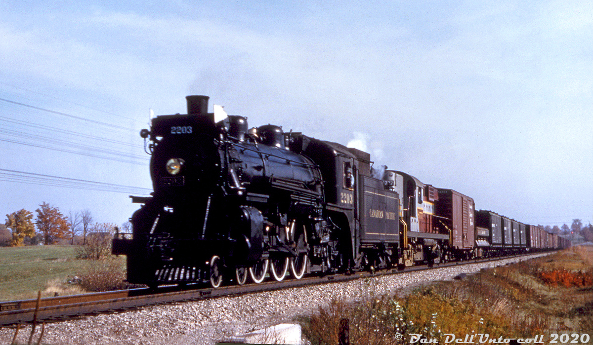 Flying white flags up front, CPR G1r "Pacific" 2203 is the westbound assist engine leading RS18 8777 and its freight westbound on the Galt Sub around Guelph Junction. In the steam era, a helper or "assist engine" was often needed for the westbound climb from Lambton/West Toronto to Orr's Lake. Upon arrival at Orr's Lake, the assist locomotive (usually placed in front of the road engine) would then uncouple and run back light power to Lambton for the next assist duties. 2200-series Pacifics like 2203 were often assigned as assist engines out of Lambton roundhouse.

2203 was originally built at CP's Angus Shops in September 1906, and ran out her final years in the Toronto area before being scrapped in August 1960, at the end of the steam era. CP RS18 8777 on the other hand, would become a regular at Guelph Junction: rebuilt as RS18u 1861, it would be sold to the Ontario Southland Railway in 1998, repainted as OSRX 181, and assigned to the Guelph Junction Railway out of Guelph Junction.

Original photographer unknown (duplicate slide, Bill Price maybe?), Dan Dell'Unto collection.