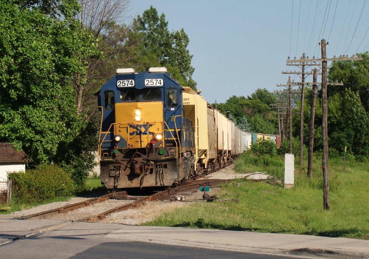 These rails haven't seen a train since October 2 2013, however the municipality of Chatham-Kent - who had owned the land for years - recently sold the line to a numbered company out of Ottawa. There aren't too many details available publicly about this sale yet but we do know it's been sold. One can only speculate what the future holds for this property now that someone clearly has interest in it. Back when trains were running, we see CSX 2574 leading a 25 car local through town on their way back to Sarnia after switching SW CO-OP and Tupperville.