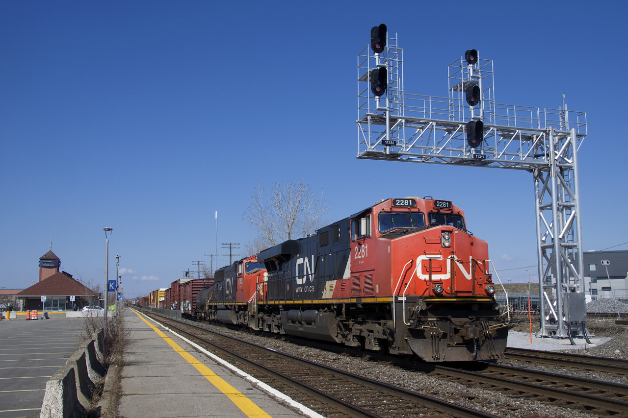 CN 368 with CN 2281 & CN 5763 for power is passing underneath a new signal gantry which was put into use just this past Wednesday, replacing a much older signal gantry. At left the long-term parking at Dorval Station is nearly empty. Normally it would be just about completely full, but today it only had a single car parked there.