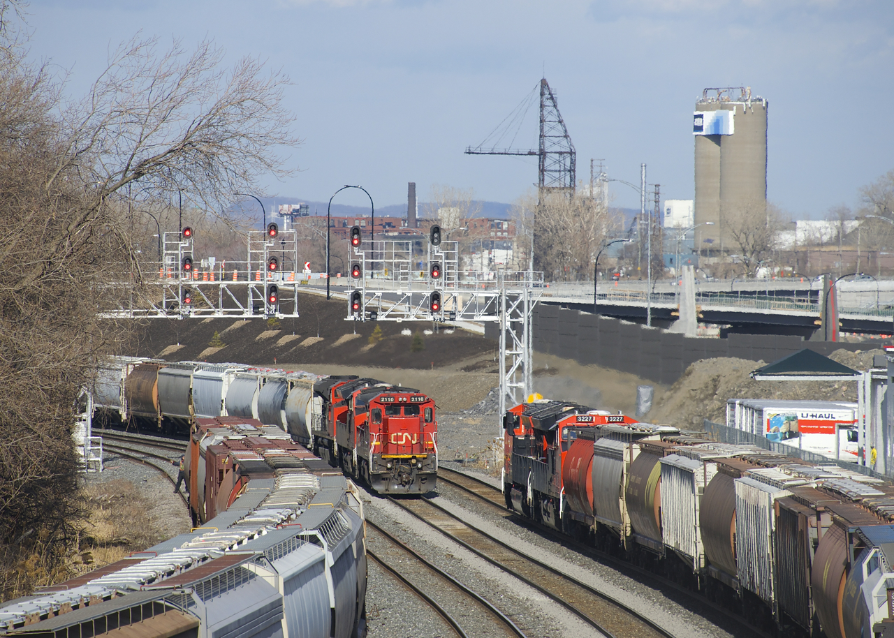 GE's built 28 years apart meet as CN 527 with CN 2110 leading is passed by grain train CN 874 with CN 3191 and 3227 up front (and CN 3887 is on the rear). CN 527 has CN 3058 and CN 8816 trailing and is stopped before it backs up to drop off cars on Track 29. CN 874 has 121 grain loads and is about to change crews at Turcot Ouest before continuing on towards Quebec City.