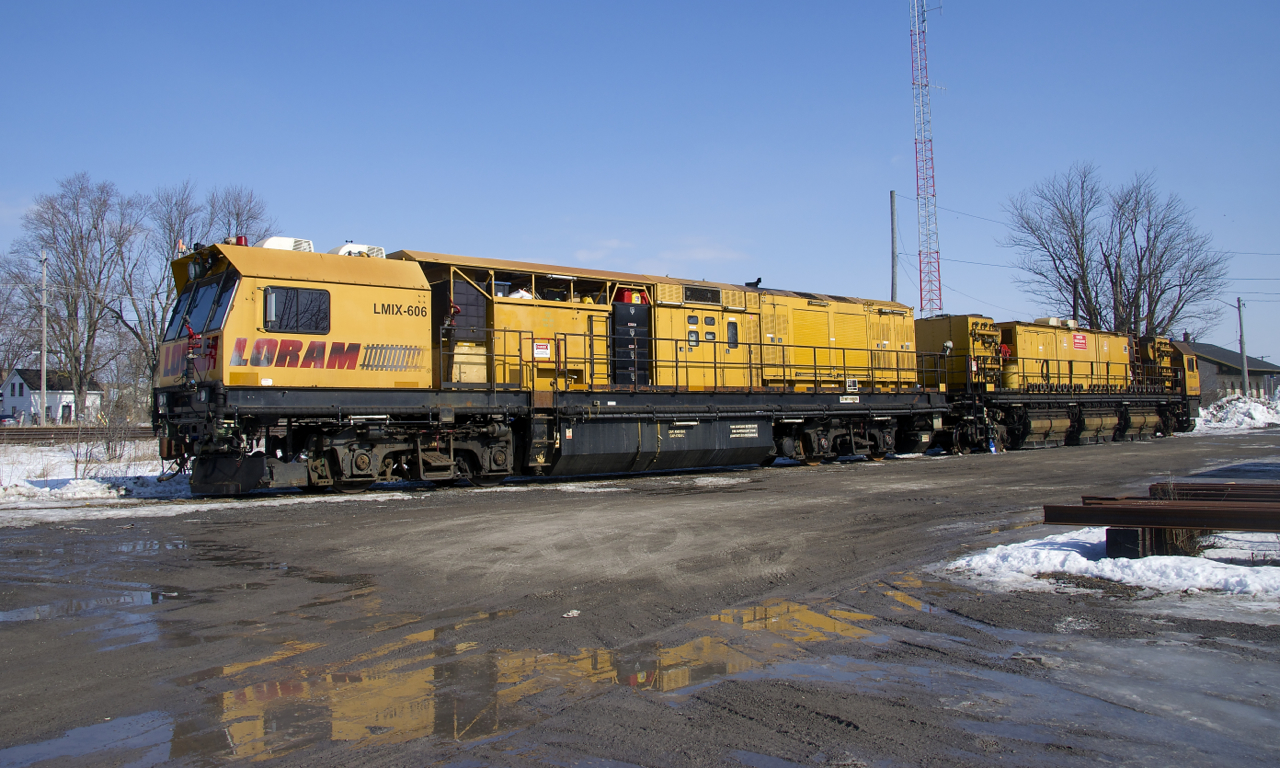 A Loram rail grinder is at rest near the venerable Napanee Station, built by the Grand Trunk Railway in 1856 and barely visible at right.