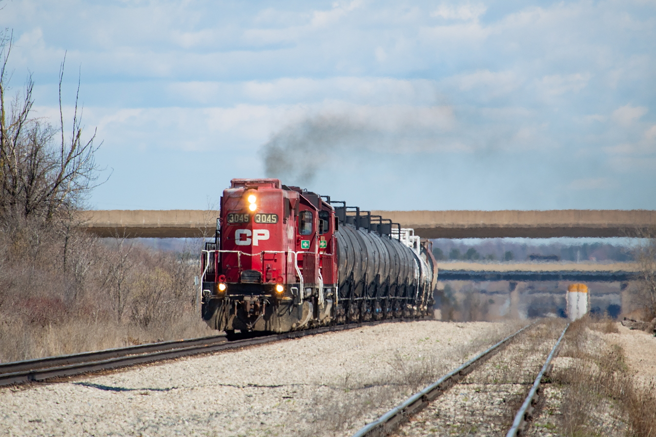 CP TE11, with CP 3045 and CP 2263, has just summited the grade out of the Welland Canal Tunnel Cut, and is making its way back to CP’s Welland Yard. In tow is traffic picked up from CN at Southern Yard, with tanks for Chemtrade in Niagara Falls, tanks for Innophos in Port Maitland, and a hopper for Washington Mills in Niagara Falls. The bridges in the background are Highway 58 and Canal Bank Street, and the siding at right is CP’s Rusholme Siding (formerly Brookfield). Aside from leaving just enough space to allow headroom for CP and CN to access Trillium’s Cayuga Spur to get into Feeder for interchange with Trillium, this 20,000+ foot siding is largely jammed with racks in storage. Welland Yard and the Stevensville Spur also have a considerable amount of racks stored presently as well.