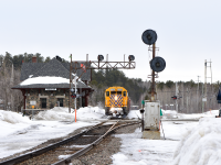 Ontario Northlands daily Englehart to North Bay road freight rolls through the heart of Temagami Ontario on their way South. GRS searchlights which used to guard the South end of the siding here sit dormant awaiting their eventual removal. To the right of the frame a mast still stands which used to hold a semaphore as well as the 1907 build station which no longer see's passenger service.