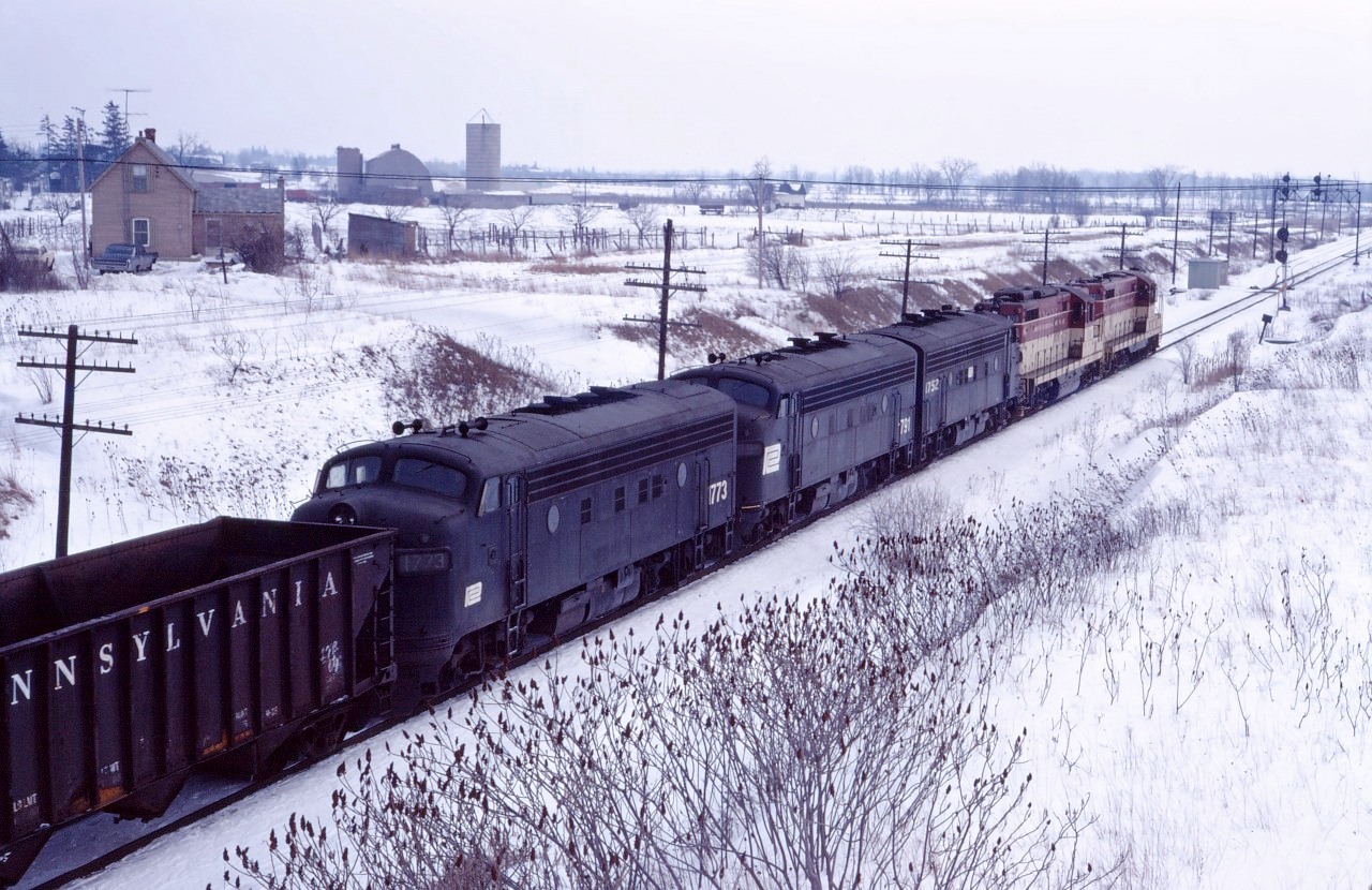 A late Toronto-Hamilton-Buffalo run-through train TF-2 crests the escarpment at Vinemount on a winter's day in March 1972. Note the TH&B "puller engines" (a GP7 and a GP9) assisting the through power (PC F7As 1752, 1791, and 1773).