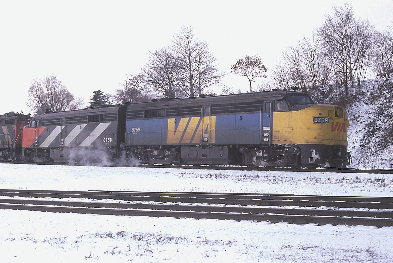 Because only two MLW FPA-2 units survived the initial 6 on CN to the VIA Rail age, it was certainly gratifying to one morning roll up into the parking area at Bayview Junction just in time to see #72 roll eastward, with both survivors up front!!  VIA 6759 and CN 6758 !! This was the very early years for VIA and the second unit had not yet met the paint shop.
Of the six units that came to CN in 1955, (6750-6755), four were retired by 1975; the other two, 6751 and 6755 were renumbered 6759 and 6758 after rebuild (FPA-2u) and sold to VIA in 1978. and they too were retired by 1978. The 6758 soldiers on with the New York & Lake Erie, same number.
Unfortunately for me the passenger moved off before I could grab another shot of the consist. One can just barely make out CN 4100 as the third unit, probably 4 in total.