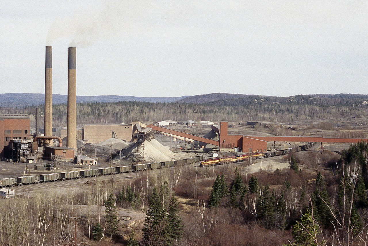 The great (or infamous) Algoma Sinter Plant is no longer. It shut down not long after this photo was taken, and the whole complex, along with the railroad, was demolished and removed. In 1997 Algoma Ore had decided to cease all operations in the area.
This image shows WC 6604. 6655, 3012, and 6506 bringing more cars in tow in order to switch out the plant.