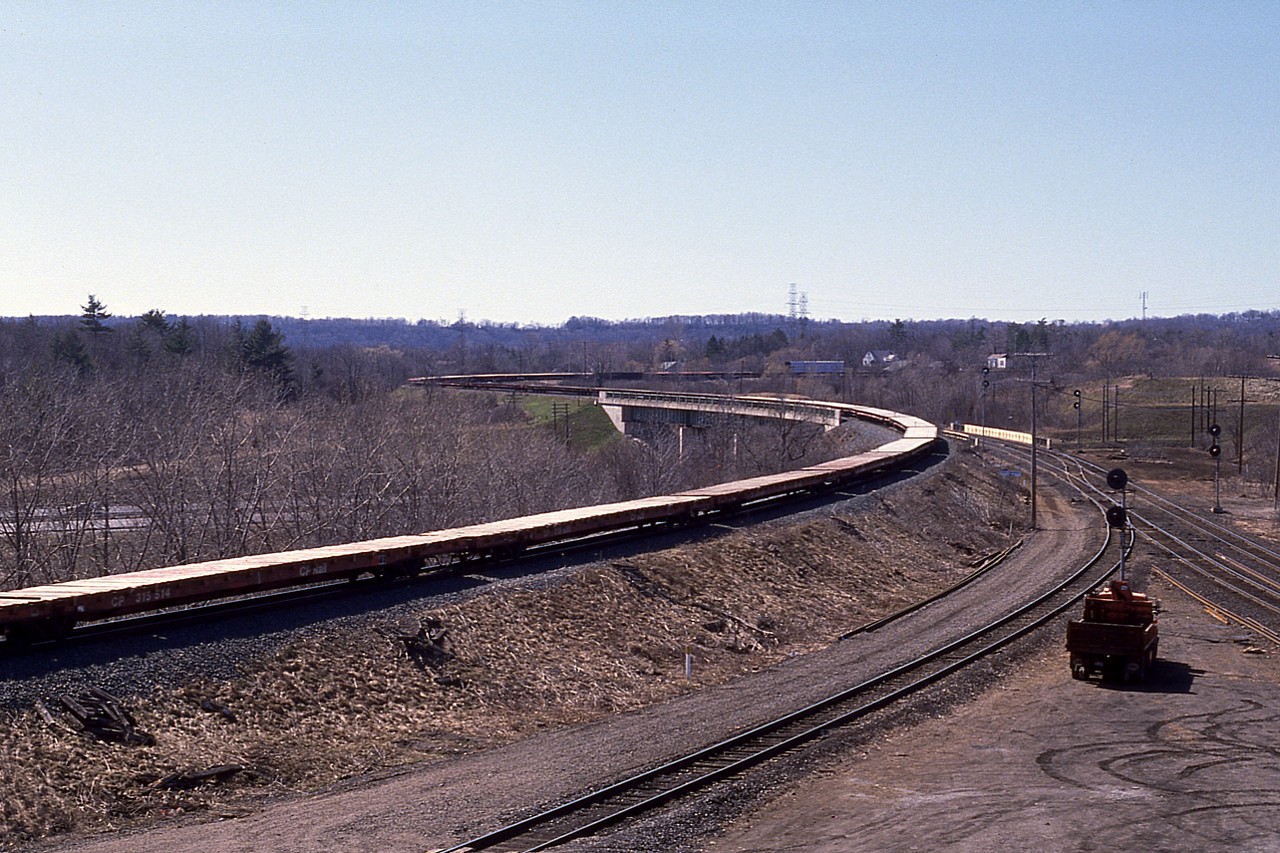 In case some of you 'rolling stock' fans might find this of interest. I did not record the power on this train so had neglected to shoot a pix of it; probably because it was "same old" at the time, and against the sun, but grabbed a shot of the consist. Seemingly endless 'specialty flat cars' only broken up by what looks to be a lumber car in the distant background. Wondering where they are going? I noticed a couple with visible handbrakes as well.  The train was heading into Hamilton from Guelph Jct.  Something a little different.