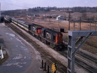 A CN morning passenger train speeds eastward past Aldershot Cold Storage, about to pass under Waterdown Road.<br>
Powered by MLW RS-18 CN 3104 and GMD GP40 CN 4016, the train has a Steam Generator unit, 5 coaches, and looks like a baggage car trailing.<br><br>
The businesses between the tracks and Highway 403, the nearest with Esso signs, are long gone.<br> 
Perhaps they were related to the Cold Storage operation; I wonder how that area used to be accessed.<br><br>
The major roads and railway remain, but much has changed since 1975.