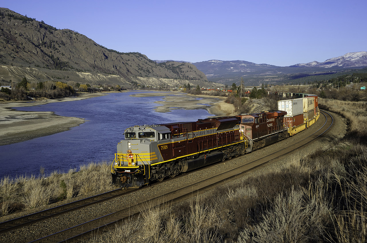 CP SD70ACU 7018 speeds towards a crew change at Kamloops, following the shores of the South Thompson River with 101-07's train between Ducks and Bromley on the north track of CP's scenic Shuswap Sub.