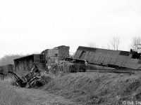 Cleanup efforts are underway on the aftermath of a wreck at Fort Erie, showing CN M636 2318 and an SD40 (possibly 5029) off the rails and with its cab ripped open. A few cars and caboose are visible in the adjacent ditch. 