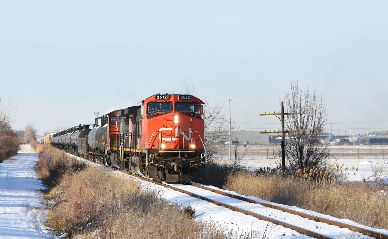 CN 439 trundles along the jointed rail of the Pelton spur past wireless code line poles and the property line for Windsor Airport.