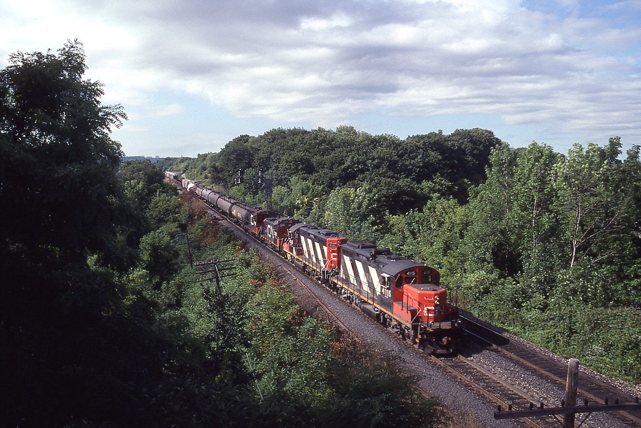 What a nice early fall-type morning. Clear, and you can almost feel the promise of a nice day in the offing. I'm on the overhead walk bridge to Laking Gardens, as almost all the local viewers would know; and out of Hamilton comes this rather lengthy train, judging by the power is the local, but long enough to be a mainline distance freight. Up front are CN 4115, 4136, 7316, 7102.  The last unit is a "sweep". Interesting bunch !!