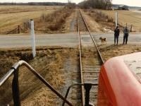 A view from the cab of CN 4115 as it powers the rail salvage train towards Line 60, which was the first crossing west of Palmerston on the CN Newton Subdivision. As well, a couple onlookers and a companion have gathered at the small crossing to take in the historic action. Earlier that day, the rail train had slowly rolled through the town of Palmerston for the last time and was powered by CN GP9RM’s 4115 and 4140. During April 1996, CN had removed the last sections of the Newton and Owen Sound Subdivisions that remained between Harriston and Stratford. Note- Photo taken with permission of the rail train crew. 