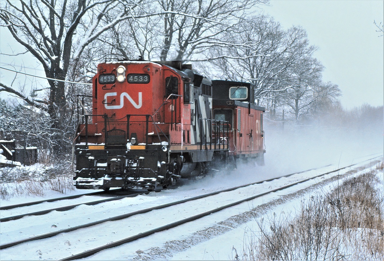 CN 4533 has a van hop up to track speed just east of Clarkson, Ontario and a cold January 1985 afternoon.