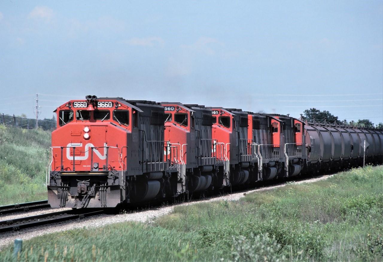 CN GP40-2L(W) 9660 leads 4 others westbound on the York Sub as it approaches the diamond at Snider, Ontario with 77 loaded "pots" and a caboose bringing up the rear.  I forget the train number that CN assigned to this movement, but I'm certain it would have last received train orders at Washago which would have identified it as Extra 9660 South.  Units were: 9660, 9560, 9461, 9658, and 9579.
