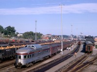 The Paris Street overpass in Sudbury, Ontario, provided an excellent vantage point to witness the combining of the Montreal and Toronto sections of CPR passenger trains.  On Sunday, August 20, 1967, I was on hand to enjoy the various switching moves as the Expo Limited took the scheduled 45 minutes to prepare for its 8.35 a.m. departure for Vancouver.  Later in the day, I would see the splitting of the Canadian into its Montreal and Toronto sections. <br> <br>

Budd sleeper-dome Banff Park is prominent in the foreground as a yard crew working with S-4 7092 has prepared the rear of the train for departure.  Mate 7090 worked the coaches on the west end.  In the distance, connecting RDC-2 9100 would depart as Train 427 for Sault Ste. Marie.<br> <br>  

Although I did not record the consist, CPR's Assignment of Space booklet confirms that the Park car would continue from Montreal to Vancouver.  The Montreal train also included a 10-6 homebuilt Grove series sleeper, followed by an N, S or T series 12 section-1 drawing-room car, and an R series 8 section, 1 drawing-room, 2 double bedroom car.  Then a 12-1 sleeper such as Scotstown, which S-4 7092 had just set off after its trip from Montreal.  An A or W series heavyweight diner from Montreal would turn back to that city on Train 6.  Toronto cars arriving on Train 15 included an R series car and two 12-1s for Vancouver. <br> <br> 

The switcher marshalled the Toronto cars ahead of the R series sleeper from Montreal.  An A or W series diner just ahead of the Grove car would continue from Toronto to Winnipeg and a replacement provided for the remainder of the run to Vancouver.  In Winnipeg, a switcher placed a 500 series Skyline cafe dome between the sleepers and coaches.   The stopover in Winnipeg also saw the addition of another Grove series sleeper for Vancouver.  Finally, in Regina, an R car series car was added for Vancouver.  In both cases, the switching placed the sleeper immediately behind the Skyline. <br> <br>

Three of CPR's newest mechanically air-conditioned 2200 series coaches rode on the head end behind a 4700 series baggage car.  Typical power from Montreal to Calgary was two boiler-equipped MLW RS-10s or FPA-2s.  The Toronto leg drew a similar, single unit.  A pair or trio of boiler-equipped GP9s was normal west Of Calgary. <br> <br>

The overall effect was a one-season re-creation of CPR's classic Dominion, which had crossed the country in heavyweight style on a four-night schedule for decades until Monday, January 10, 1966.   The Expo Limited was part of the CPR's celebration of Canadian Confederation.  Another significant contribution was the Canadian Pacific Pavilion at the World's Fair, Expo '67 in Montreal.  The Expo Limited not only served tourism in the Canadian Rockies but took travellers to Expo '67.  It was a grand year!  