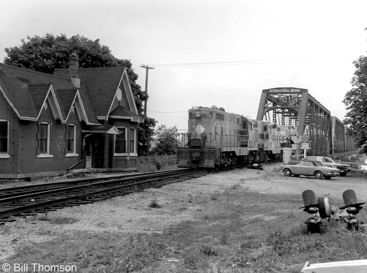 A Conrail transfer from the US lead by a pair of former EL Geeps crosses the International Bridge into Fort Erie in July of 1976, passing by the old station. It's three months since Conrail had been formed from a handful of bankrupt eastern railroads, and mixed power in their former owner's colours (often unpatched and not yet renumbered) was very common. Lead EMD GP7 unit Erie Lackawanna 1200, originally built for the Erie Railroad in 1950, would be patched and renumbered to Conrail 5930 by the next year, to match the hybrid PRR-NYC numbering system that Conrail adopted. Note the old classic "barrel headlight" it still sported, along with spark arrestors on the roof.