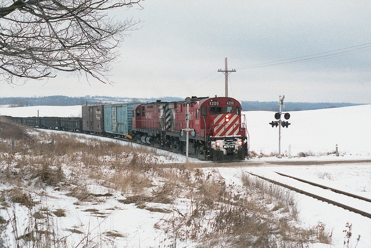 Nothing like posting a snow scene on a day it is sweltering outside. :o) This is the TH&B Nanticoke train from Hamilton down to the Lake Erie steel facility; and it is seen here about to go over Slote Road very close to where it joins Mineral Springs Rd. Rather than the Chessie units that were brought in for frequent use on this run, today it is with a couple of CP MLW C-424s up front; nice to see the first of the series, 4200, leading 4235.  The 4200 was the only one of the series built in 1963, and it was retired in 1995.