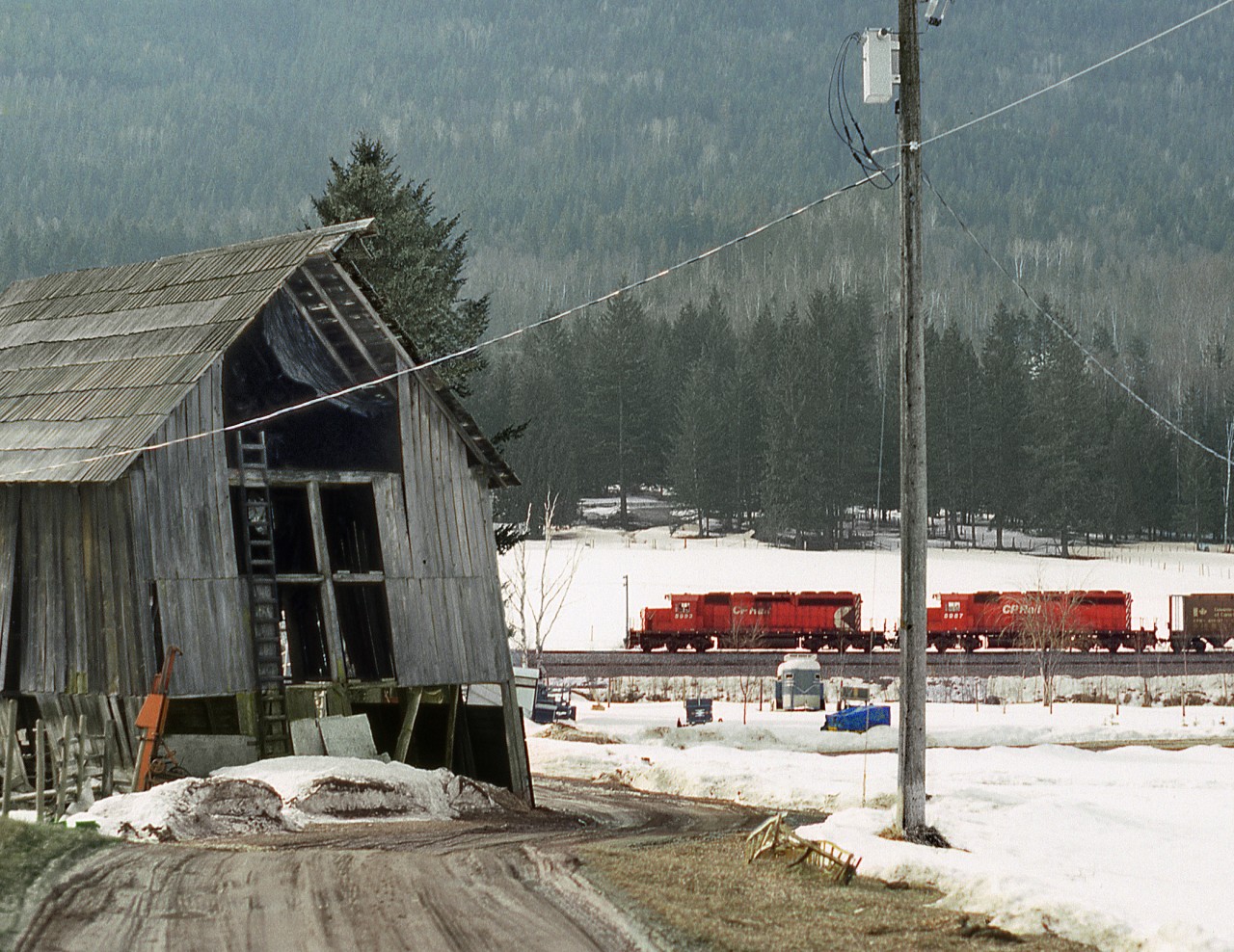 An eastbound grain empties heads downgrade from Notch Hill Summit passing a derelict bar. Notch hill is ridge between Salmon Arm and Chase between the two arms of the U shaped Shuswap Lake