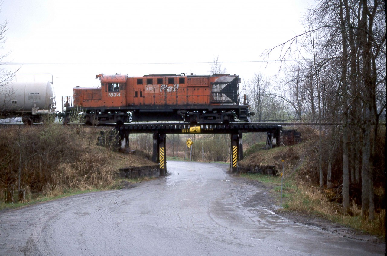 The Ottawa Central acquired CN trackage between Ottawa and Pembroke, Ontario, on their truncated mainline to Capreol.   The agreement also included trackage rights on VIA Rail between Coteau and Ottawa.  The OCRR began operations on Thursday, December 31, 1998, and continued for almost ten years until Monday, November 8, 2008, when Canadian National repurchased the assets from the Ottawa Central's owner, the Quebec Railway Corp.   The Ottawa Central also contracted with the Ottawa - Carleton Regional Municipality to operate the former CN line to Arnprior.  Ironically, CN is now discontinuing service on these lines, and the future of the Arnprior line is uncertain.  

It is on the latter line where I caught the westbound local to Arnprior at South March, Mileage 5.5 of the former Renfrew Sub, at 925 on Wednesday, May 5, 2004.   RS-18u 1834 wears the New Brunswick East Coast name as it served for a time on that subsidiary of the Quebec Railway Corp.  

The CPR acquired RS-18 8776 from MLW in May 1958 (Serial 82457), upgraded it in June 1985, and renumbered it 1834.  CP Rail sold the unit to the NBEC in April 1998, who later leased it to the Ottawa Central.   CN acquired the RS-18u with the repurchase in 2008 and retired it the same year.