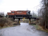 The Ottawa Central acquired CN trackage between Ottawa and Pembroke, Ontario, on their truncated mainline to Capreol.   The agreement also included trackage rights on VIA Rail between Coteau and Ottawa.  The OCRR began operations on Thursday, December 31, 1998, and continued for almost ten years until Monday, November 8, 2008, when Canadian National repurchased the assets from the Ottawa Central's owner, the Quebec Railway Corp.   The Ottawa Central also contracted with the Ottawa - Carleton Regional Municipality to operate the former CN line to Arnprior.  Ironically, CN is now discontinuing service on these lines, and the future of the Arnprior line is uncertain. <br> <br>

It is on the latter line where I caught the westbound local to Arnprior at South March, Mileage 5.5 of the former Renfrew Sub, at 925 on Wednesday, May 5, 2004.   RS-18u 1834 wears the New Brunswick East Coast name as it served for a time on that subsidiary of the Quebec Railway Corp. <br> <br>

The CPR acquired RS-18 8776 from MLW in May 1958 (Serial 82457), upgraded it in June 1985, and renumbered it 1834.  CP Rail sold the unit to the NBEC in April 1998, who later leased it to the Ottawa Central.   CN acquired the RS-18u with the repurchase in 2008 and retired it the same year.  