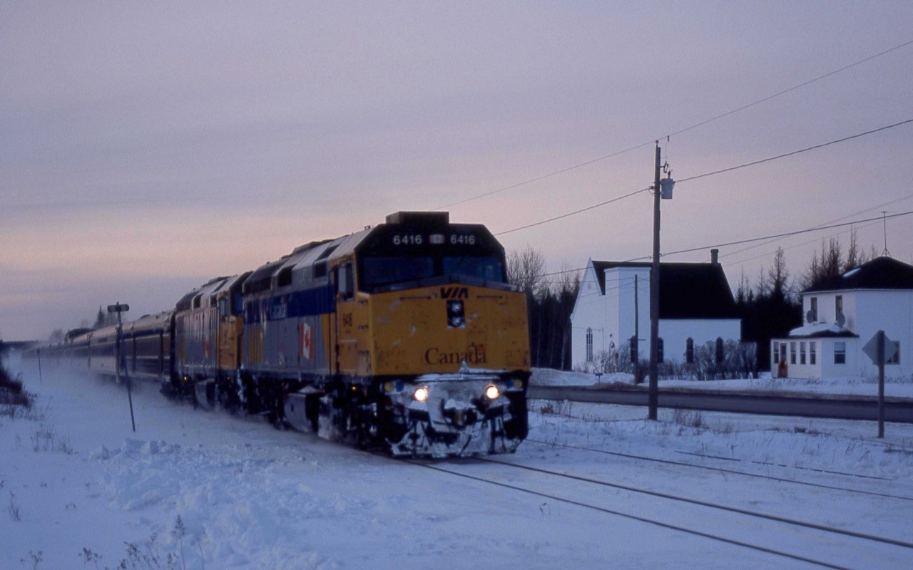 VIA Train 14 was running some six hours late as it speeds through Harcourt, New Brunswick, about 5 p.m. on a wintery Monday, March 7, 2005.   It is passing the deconsecrated Wesley Memorial United Church a few hundred yards north of the site of the CN station at Mileage, 24.4 of the Newcastle Sub.     

The Ocean, on its way to Halifax, Nova Scotia, had a healthy consist of F40-PH2s 6416 and 6426 with baggage car 8619, coaches 8139 and 8127, dome 8505, diner Louise, Chateau sleepers Laval, Marquette, Papineau, Viger, Radisson, Jolliet and dome observation Laurentide Park.  At Catamount, it would meet Montreal-bound Train 15, a Renaissance set behind units 6421 and 6413.   

The Newcastle Sub extends from Catamount 173.2 miles north along the east coast of New Brunswick, ending at the division point of Campbellton.  This route of the Intercolonial Railway linked Nova Scotia and New Brunswick to central Canada.  Its completion on Saturday, July 1, 1876, satisfied one of the conditions that had brought the eastern provinces into the Canadian confederation.  The Ocean began running on this route on Sunday, July 3, 1904, and had recently celebrated its 100th year of service as North America's longest continuously operating name train.