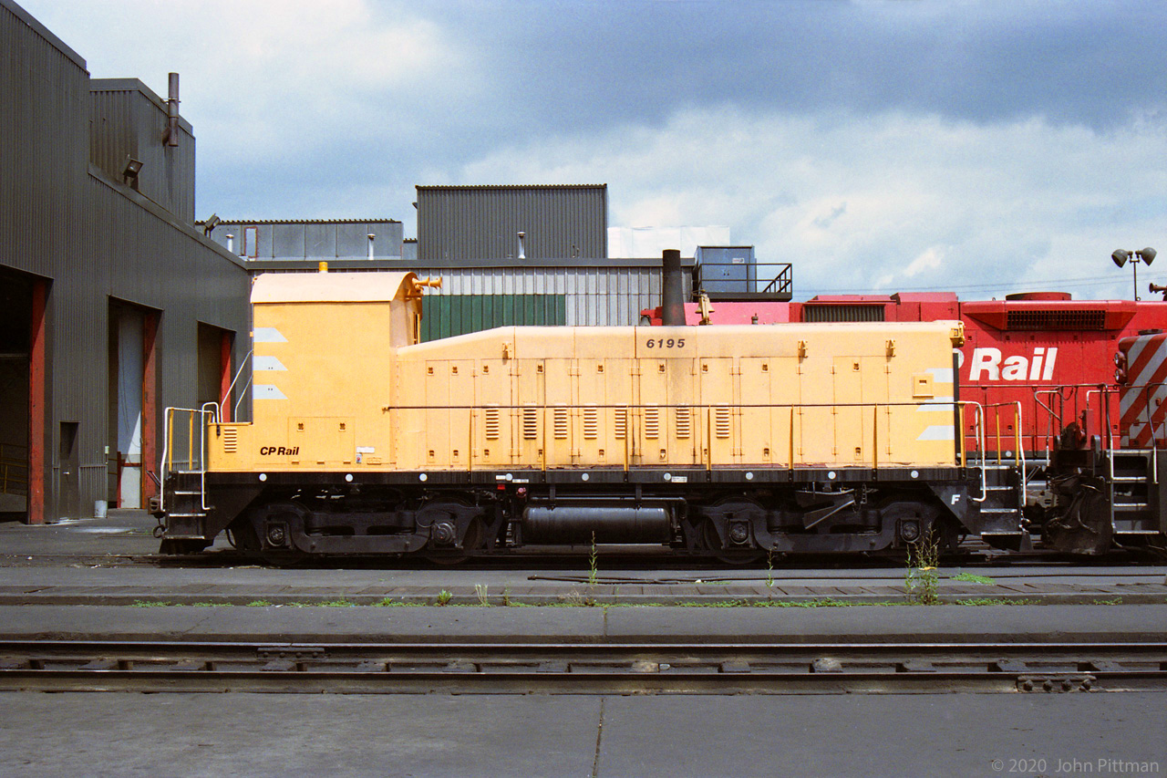 CP 6195 was a remote-control switcher, seen at the Alyth Diesel Shop in Calgary.
It was a GMD SW900 originally built as CP 6716 in 1955, rebuilt to CP 6195 in 1991.
Visible modifications included covering all cab windows and this high-viz paint scheme.
CP disposed of it in 2003.