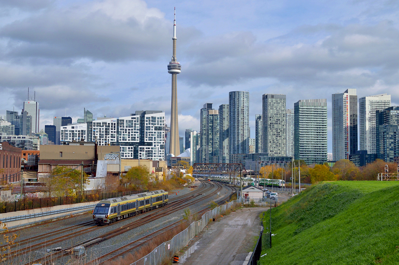 A westbound UP Express train leaves the USRC behind dropping downgrade to pass beneath Strachan Avenue as it heads towards it's few stops on the way to Pearson International.  In the background a westbound GO train heads onto the Oakville Sub.