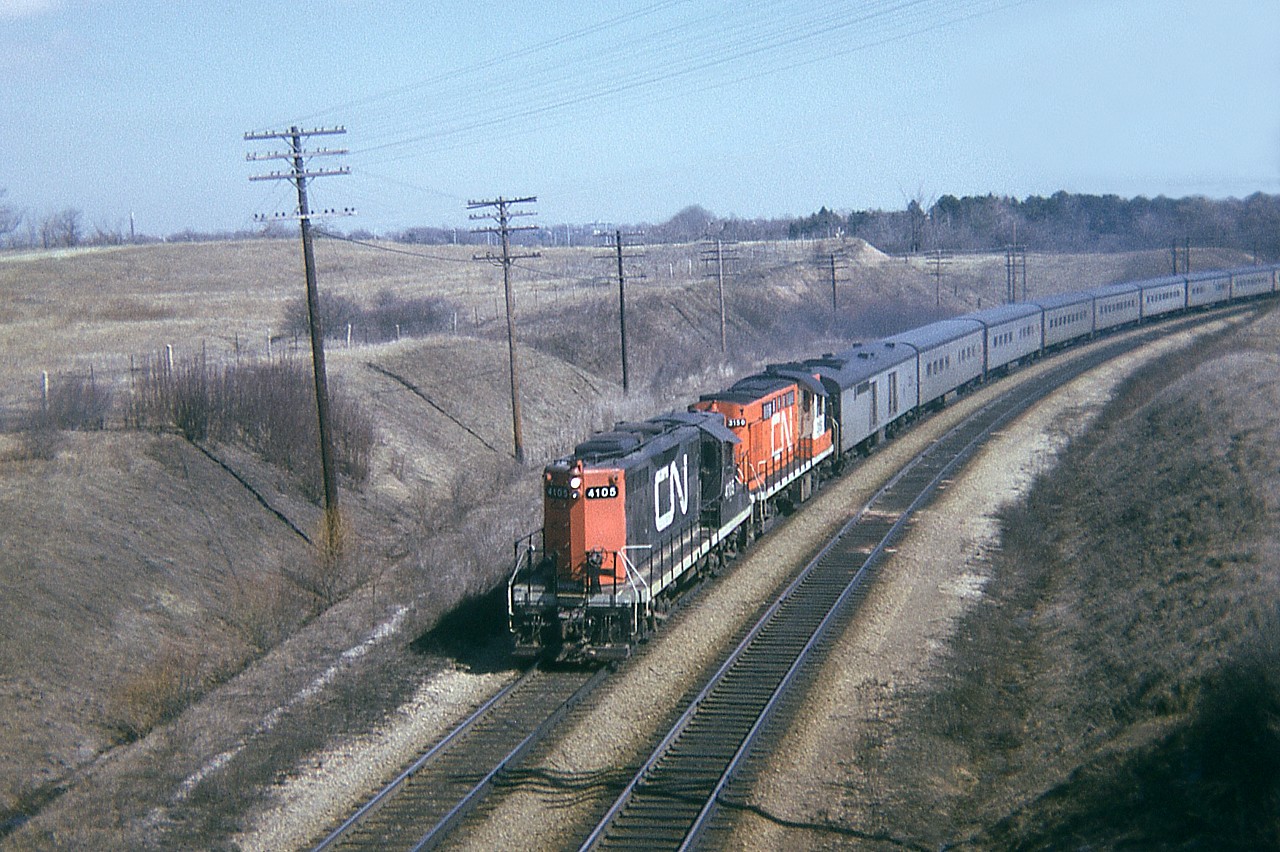 I don't know the boundary lines so I am going to call this Dundas. (Is it Burlington? Is it Hamilton?)  Anyway, this is shot from the CP bridge over the CN just to the east of Old Guelph Road. Train is close to Mile 1. Not a location that is easy to get to any more. The obvious change over the years is the surprising lack of trees back then. Its barren!!! Somebody sure did a good job of manicuring  !!!
I'm think that is the old Burlington Brick Co chimney seen at upper left in the photo. CN 4105 and Tempo unit CN 3150 have an impressive train.
