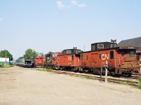 An eastbound CN business train powered by CN GP9RM's 7082 and 7083 is slowly departing Kitchener, revealing the CN local assigned units and cabooses at the time. They included; CN GP9RM's 7031, 7030 and cabooses 79817 and 79513 seen in evening light across from the VIA Rail station. 

