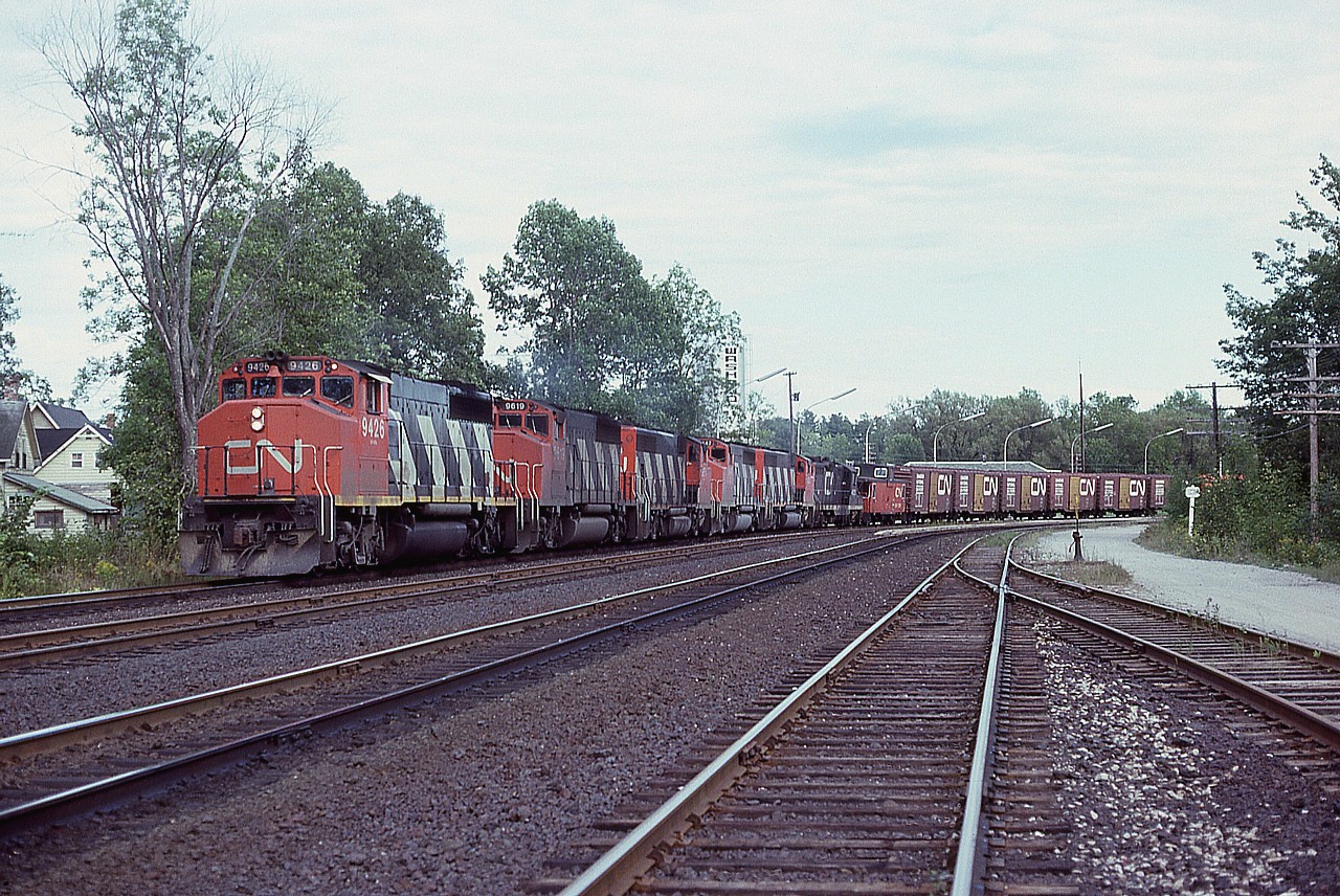 Rounding the curve at Washago is what I would consider now the 'old style' freight; with lots of power up front, as in 5 GP-40-2L wide nose,  a caboose, and a long string of boxcars.
Power is CN 9426, 9619, 9654, 9447, 9605 and 4521. The roof of the station can be seen behind the first three box.