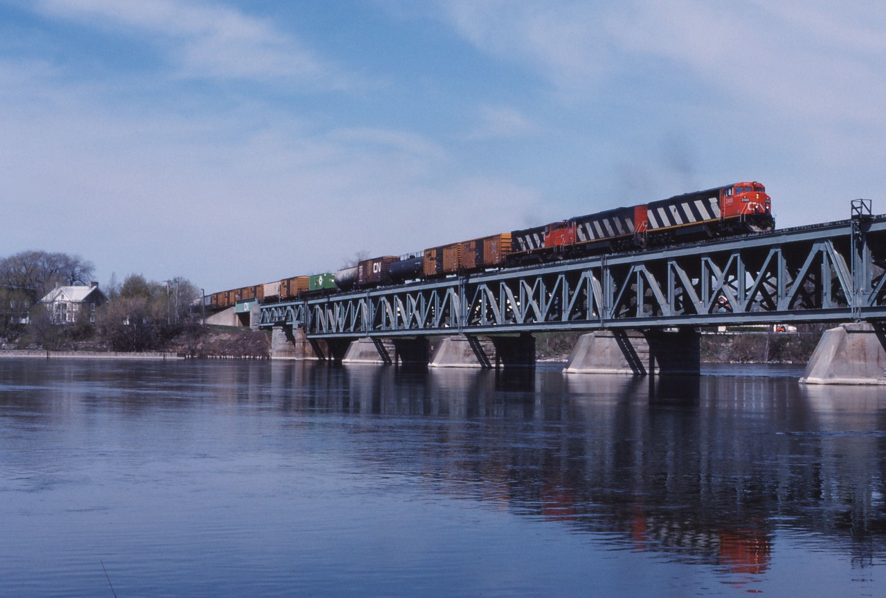 On a beautiful spring day in 1990, CN train 330 (Taschereau Yard-Gordon Yard/Montreal-Moncton)crosses the Richelieu River behind brand new C40-8Ms 2410 and 2413 and HR412 3585.