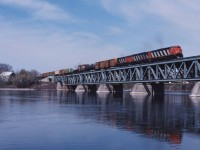 On a beautiful spring day in 1990, CN train 330 (Taschereau Yard-Gordon Yard/Montreal-Moncton)crosses the Richelieu River behind brand new C40-8Ms 2410 and 2413 and HR412 3585.