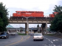 CP SD40 5408 (ex-QNS&L 212, acquired by CP secondhand in 1985) comes into view on the old Michigan Central bridge over traffic on the Niagara Parkway north of Park Street, leading CP 5560, 5563, and 5520 on a westbound entering Canada after crossing over from the states via the giant steel arch bridge over the Niagara River. Notes by Reg indicate this was a reroute due to "Indians", so presumably a local indigenous group blockade somewhere (US or Canada?) forced some extra traffic to detour through downtown Niagara Falls and over the old MCRR/CASO line (that had become part of CP's Hamilton Sub in the mid-80's).<br><br>The bridge here over the roadway remains today, unused, despite the line being removed through downtown Niagara Falls in 2001. The bridge in the background carries CN's Grimsby Sub from VIA's nearby Niagara Falls station into the US via the Niagara Whirlpool Bridge.<br><br><i>Reg Button photo, Dan Dell'Unto collection slide.</i>